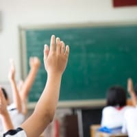 Students raise their hands in a classroom